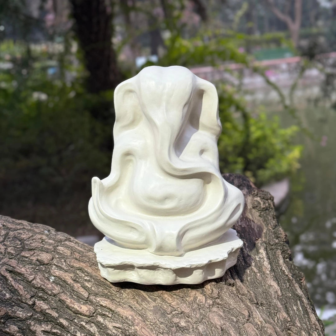 White hand painted Ganesha Abstract Sculpture of a seated figure on a tree stump with a natural background
