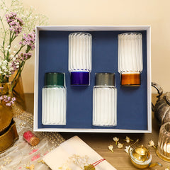 A set of four colorful highball glasses with a striped design, displayed in a gift box with a blue background. The glasses are shown in grey, blue, green, and orange colors.