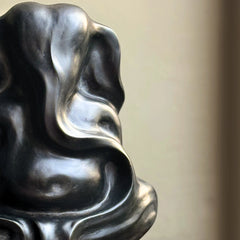 Close-up of a dark, textured Ganesha Abstract Sculpture against a blurred background