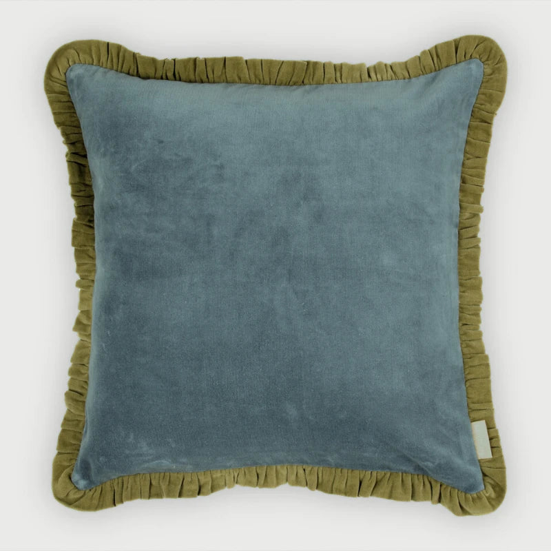 A square throw pillow featuring a dusty blue velvet center panel and an olive green ruffled border, shown against a plain light gray background.