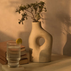 Ceramic Savanna Vase with plant and glass of water on a table with books in soft lighting