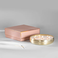 Jali Tray Candle - Gold - Oud Rose, lit multi-wick gold tray candle beside rose gold gift box
