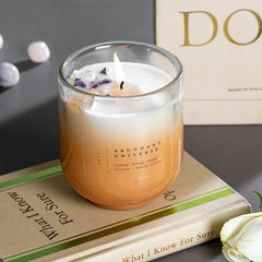Amethyst & Citrine Candles - Crystal Energy - Set of 2, lit citrus candle on a book beside Doft box