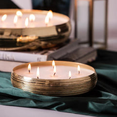 Jali Tray Candle - Gold - Oud Rose, two lit gold tray candles styled on books and green velvet