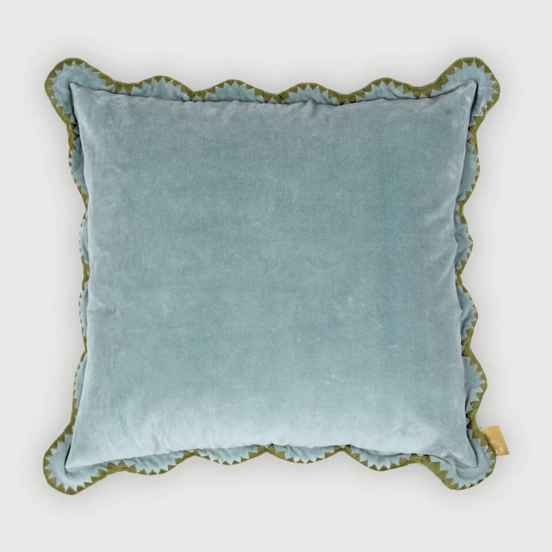 Blue velvet pillow with scalloped edge on a white background