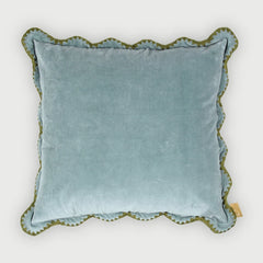 Blue velvet pillow with scalloped edge on a white background