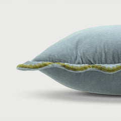Light blue pillow with green trim on a light gray background