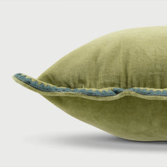 An olive green velvet throw pillow with a scalloped blue and green embroidered trim, shown in a close-up studio shot against a light gray background.