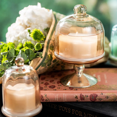 Sundance Aura Candle - Melon, two candles styled on vintage books with white flowers, lifestyle view