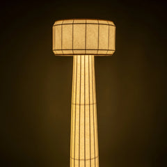 Domus Floor Lamp, Tall cylindrical lamp with a textured shade against a dark background