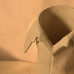 Close-up of a ceramic solis vase with a textured surface on a beige background