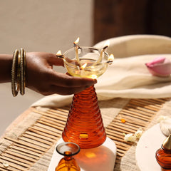 Composite Gift Box, hand holding ribbed amber tall diya with cotton wicks on woven mat