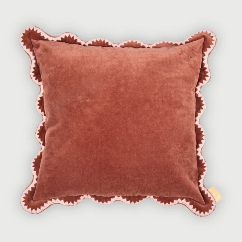 Brown pillow with pink trim on a light gray background