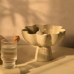 Decorative beige Sora bowl with a glass of water on a neutral background