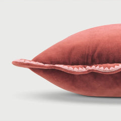 Red velvet pillow with a decorative edge on a light gray background