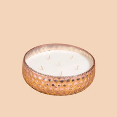 A multi-wick bowl candle in a hammered metallic bowl, featuring a textured honeycomb rose gold exterior and a white wax interior with Tranquil Lotus fragrance 