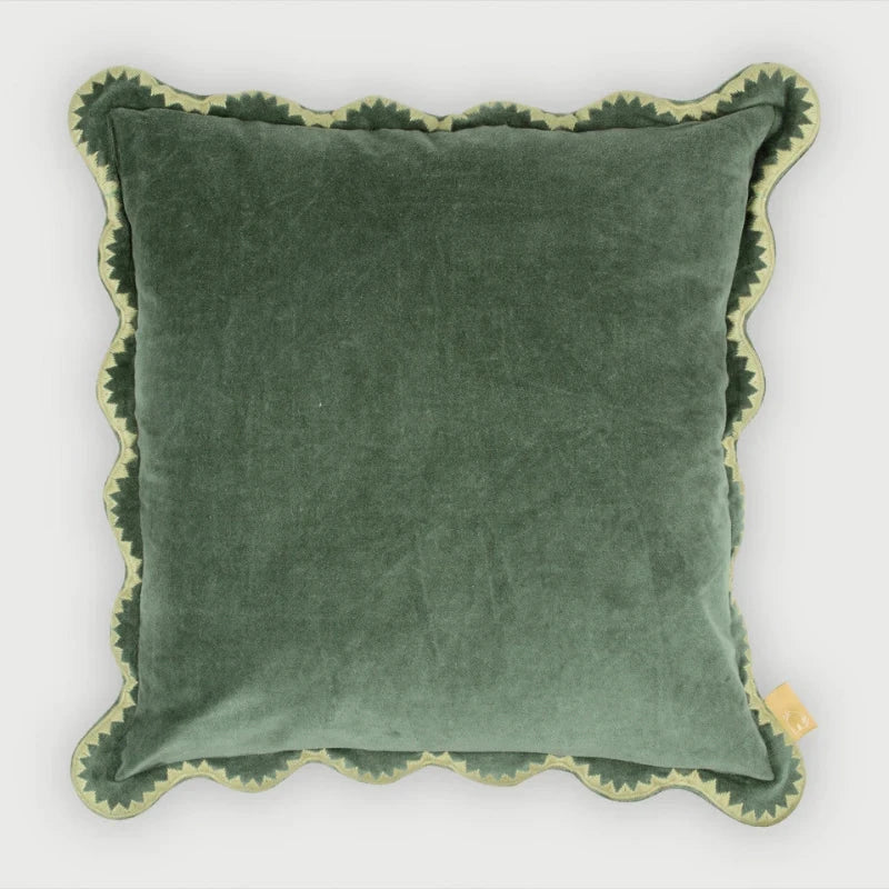 Green velvet pillow with scalloped edge on a white background