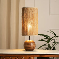 Jute Table lamp with woven shade and wooden base on a marble surface, plant in the background