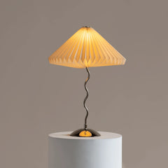 Modern table lamp with a pleated yellow shade on a gray pedestal against a brown background
