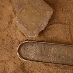 Close view of irregular finished dosa tray next to a small rock on a sandy surface