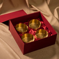Set of gold milan brass bowls in a red box on a beige fabric background