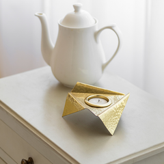 Origami Tealight holder with a hammered texture design and a candle inside, placed on a white base.