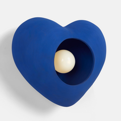 Close-up of ceramic texture and opal glass diffuser of heart wall lamp in blue color on white wall