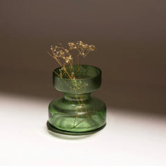 sage green tinted glass vase with dried plants on a neutral background