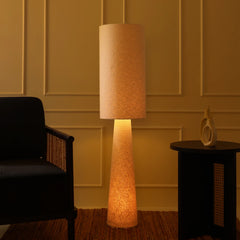 Oslo Floor Lamp with with warm lighting and textured shade in a room with a sofa and side table.