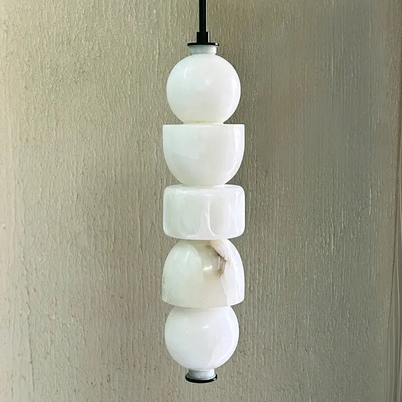 Pendant light with stacked white glass spheres on a neutral background