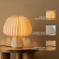 A pleated table lamp with a warm glowing shade and matching pleated base sits on a wooden table. Three callout images feature highlights: balanced ambient lighting, a laminated premium dust-resistant shade, and a 1.5 power cable