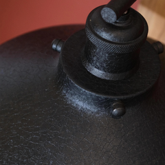 Close-up of a Leatherette Wall Lamp like a black leather with a metal clasp on a wooden surface.