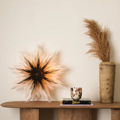 A decorative, star-shaped lamp with a geometric design, glowing with a warm light, placed on a wooden surface.