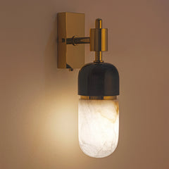 A wall-mounted Capsule Wall Light with a black marble and alabaster stone fixture, polished brass finish, and a warm white light illuminated.