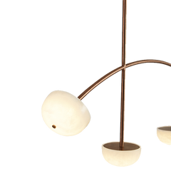A rose gold chandelier with a curved structure showing one light fixture closely.