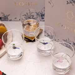 Jade clear drinking glasses with decorative elements next to a branding box of LA Dimora Selections 'KOSHA'.