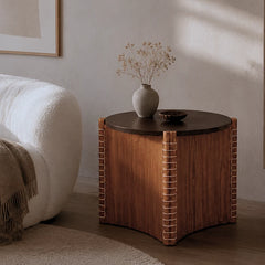 Kyvor Side Table in white ash with dark round top and cane-wrapped legs beside a cream armchair