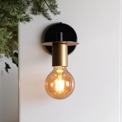 Modern Industrial Wall Light features a sleek black arm extending from a round base, complemented by a golden socket that adds a touch of luxury.