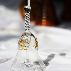 Decorative glass bell with gold designs on a white surface