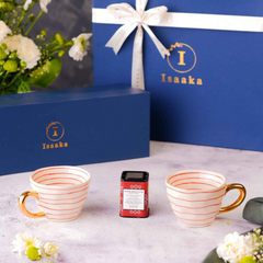 Two white and orange lines cups with gold detailing, a tea tin, presented with the branding gift box by Isaaka