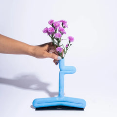 Blue vase shaped like a chair with pink flowers on a white background