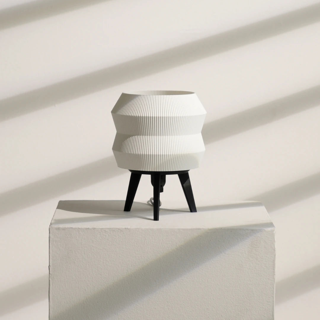 Modern white Echo Lamp with black legs on a light gray pedestal