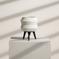 Modern white Echo Lamp with black legs on a light gray pedestal