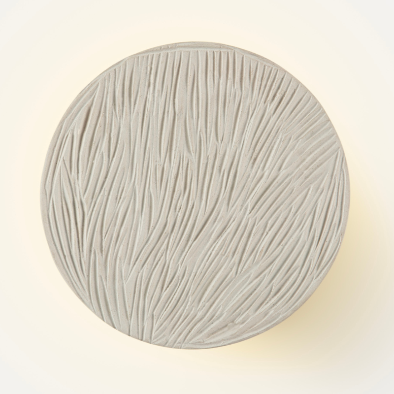 Clay disc wall lamp casting soft ambient light
