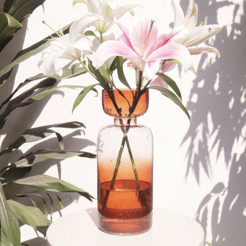 A tinted glass vase with a retro-inspired shape, featuring a gradient of vibrant colors. 
