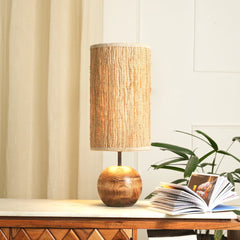 Jute Weave Table Lamp with woven shade on a wooden table next to an open book and plant