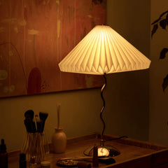 Decorative Wavy table lamp with pleated shade on a wooden surface, warm lighting.