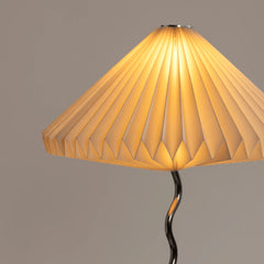 Close view of Wavy Table Lamp with pleated white shade, glowing warm light