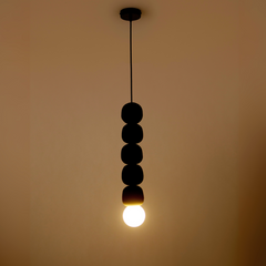 Testing 2 - Black Beaded Pendant Light, Lit Bulb Against Warm Wall