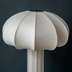Close up of white mushroom-shaped floor lamp against a dark background